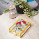 Decorative acrylic keepsake boxes styled with a plant and cozy chair in the background.