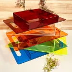 Stack of colorful acrylic trays with flat handles (red, orange, green, blue)