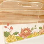 Side view of floral printed acrylic horizontal bag with handle.