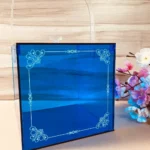 Side angle of printed blue acrylic cube box with handle.