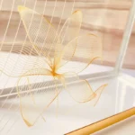 Close-up of golden floral prints on Printed Cross Bag surface.