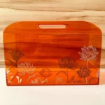 Orange acrylic horizontal bag with lotus prints, front view.