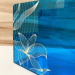 Close-up of golden floral print on blue acrylic surface.