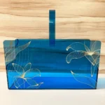Blue acrylic long basket with golden floral print, front view.
