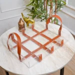 Clear acrylic tray with faux leather strap design placed on marble table.