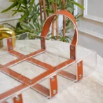 Close-up of faux leather strap and rivet detailing on acrylic base.