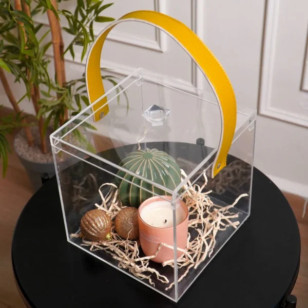 Side angle of clear cube gift box showcasing mustard leather handle and contents.