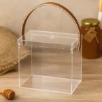 Transparent acrylic gift box styled in a modern interior setting with honey in the background.